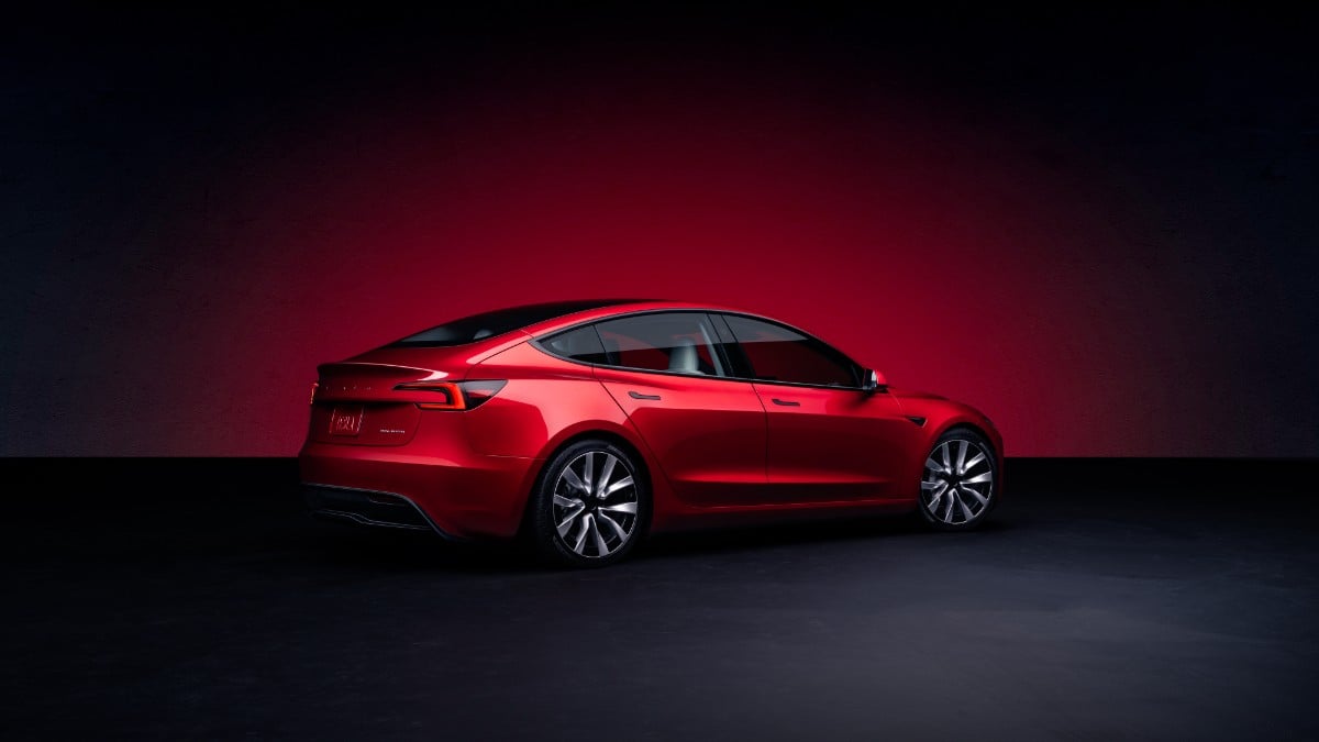 Tesla Red Tesla se muestra desde el costado contra un gradiente oscuro y un rojo dramático.